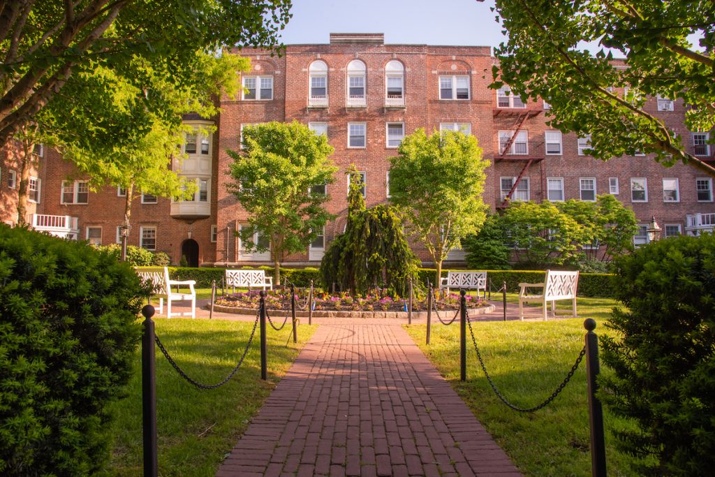 Highlands at Rye path proceeding toward building with green bushes and trees.